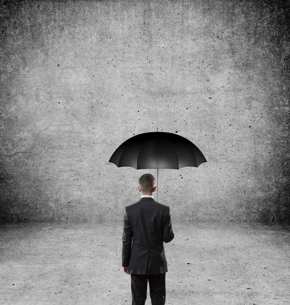 Бизнесмен с зонтиком за стеной — стоковое фото