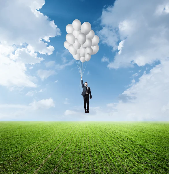 Бизнесмен, летающий на воздушных шарах — стоковое фото