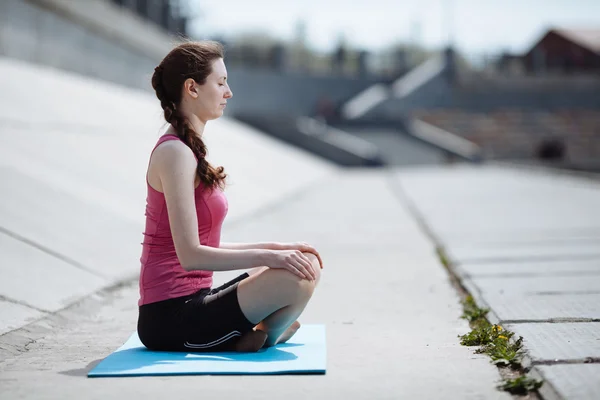 Młoda kobieta siedzi w pozycji do jogi — Zdjęcie stockowe