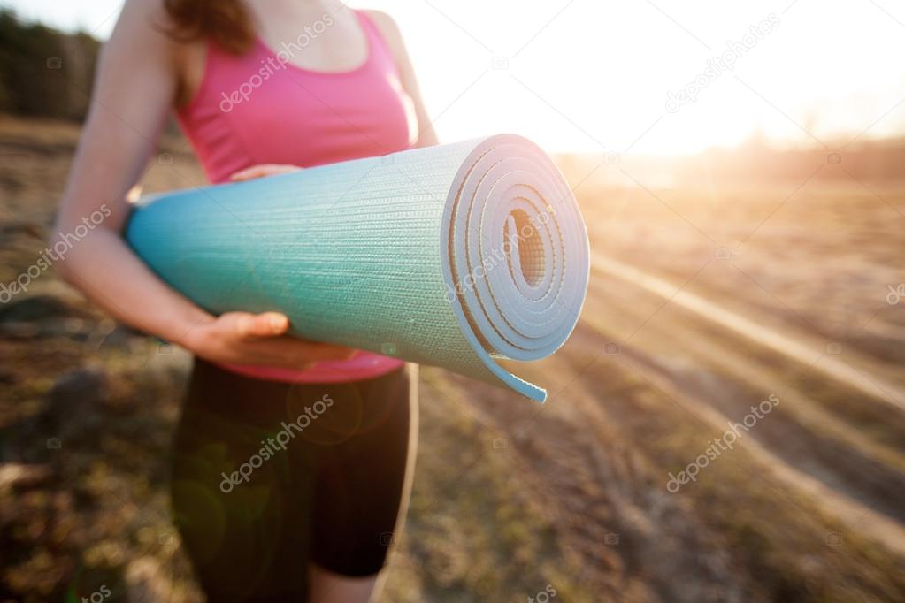 Woman walking with a yoga mat