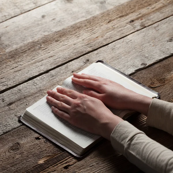 Mani di donna che pregano con una bibbia — Foto Stock