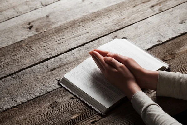 Mani di donna che pregano con una bibbia — Foto Stock