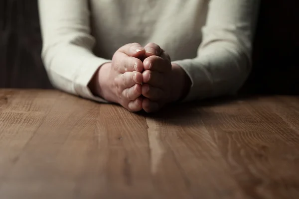 Женщина, молящаяся руками на деревянном фоне — стоковое фото