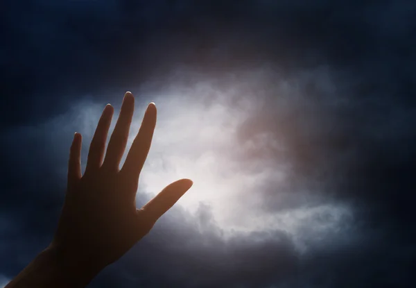 Mão alcançando o céu com nuvens escuras e tempestuosas — Fotografia de Stock