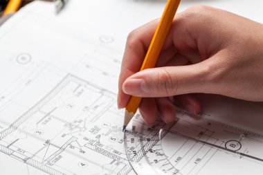 bir ev planı üzerinde bir kalem tutan kadın