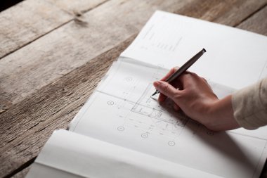 bir ev planı üzerinde bir kalem tutan kadın