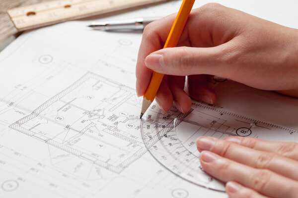 woman holding a pen over a house blueprint