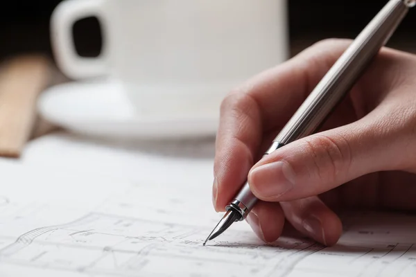 Vrouw met een pen over de blauwdruk van een huis — Stockfoto