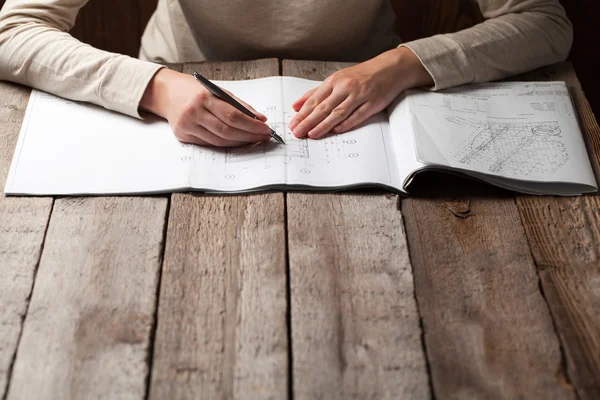Женщина держит ручку над чертежом дома — стоковое фото