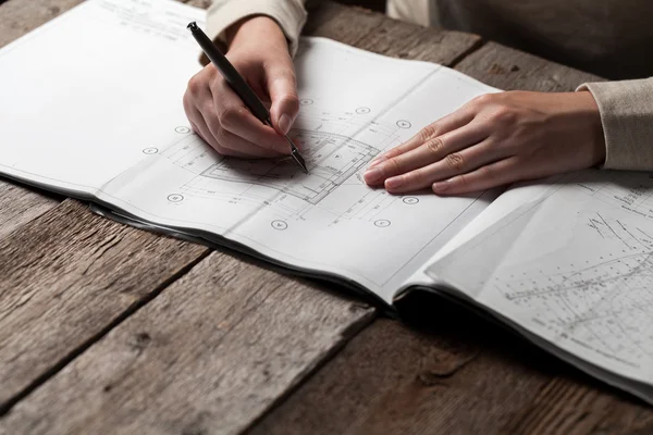 Frau hält Stift über Bauplan eines Hauses — Stockfoto