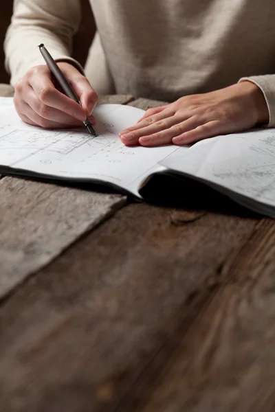 Frau hält Stift über Bauplan eines Hauses — Stockfoto