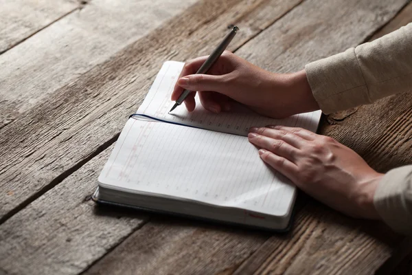 Mão escreve com uma caneta em um caderno — Fotografia de Stock