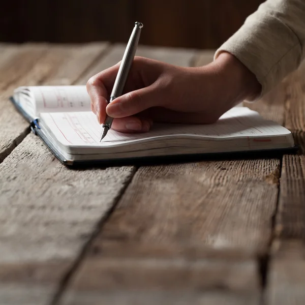 La mano escribe con un bolígrafo en un cuaderno — Foto de Stock