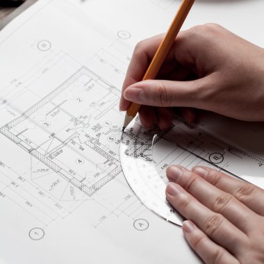 bir ev planı üzerinde bir kalem tutan kadın