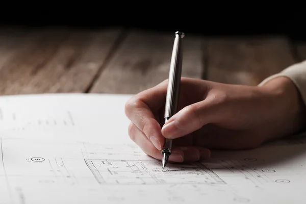 Vrouw met een pen over de blauwdruk van een huis — Stockfoto