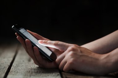 Akıllı telefon ve ahşap bir masa üzerinde tutan kız alay et