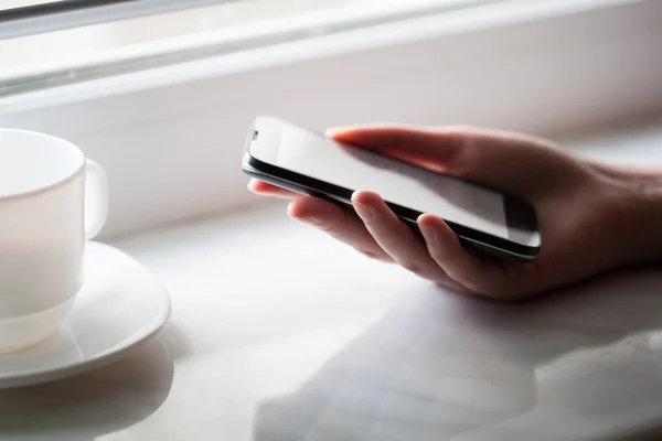 Attrappe eines Smartphones und Mädchen, das es über einen Holztisch hält — Stockfoto