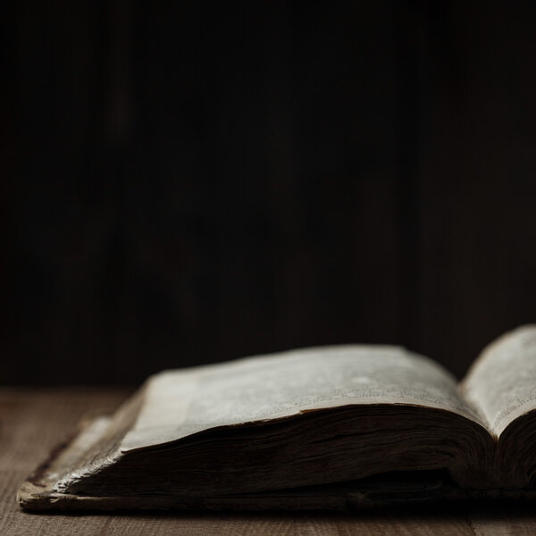 Image of an old Holy Bible on wooden background in a dark space