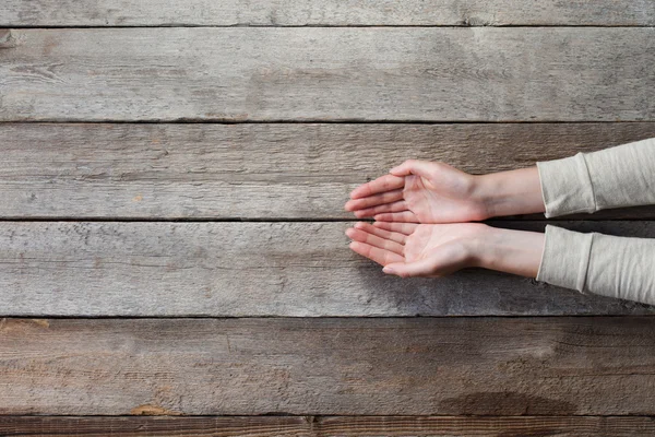 Mains de femme avec paumes ouvertes sur table en bois — Photo