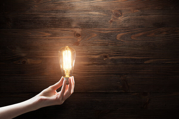 Hand holding Light bulb on blackboard background
