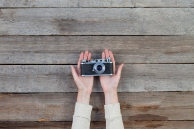 Hand holding a retro camera over wooden table