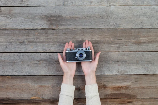 Hand holding a retro camera over wooden table — Stock Photo, Image