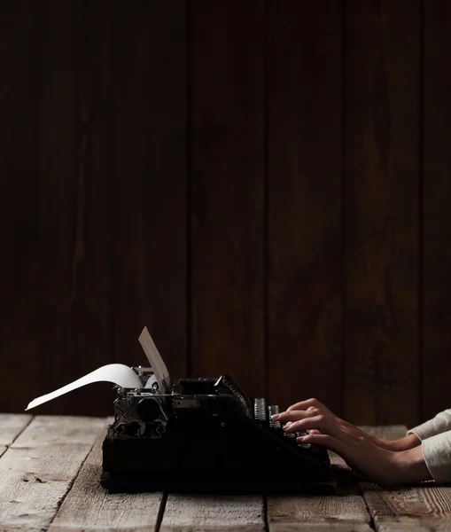 Manos escribiendo sobre una vieja máquina de escribir sobre un fondo de madera — Foto de Stock