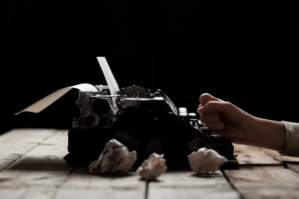 Manos escribiendo sobre una vieja máquina de escribir sobre un fondo de mesa de madera — Foto de Stock