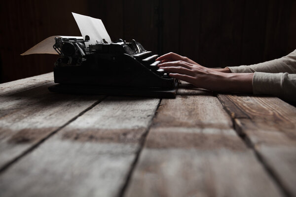 Hands writing on old typewriter over wooden table background