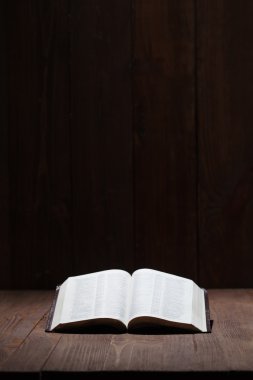 Image of a Holy Bible on wooden background in a dark space clipart
