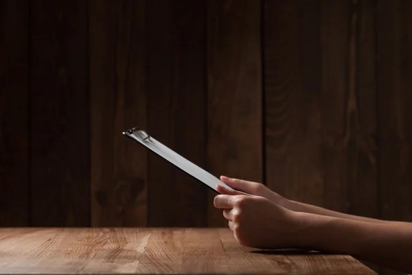 Женская рука держит бумагу над деревянным столом — стоковое фото