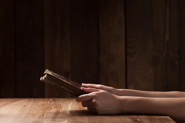 Mujer leyendo la Biblia en la oscuridad sobre mesa de madera — Foto de Stock