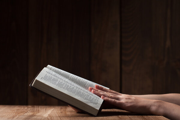 woman reading the bible in the darkness over wooden table