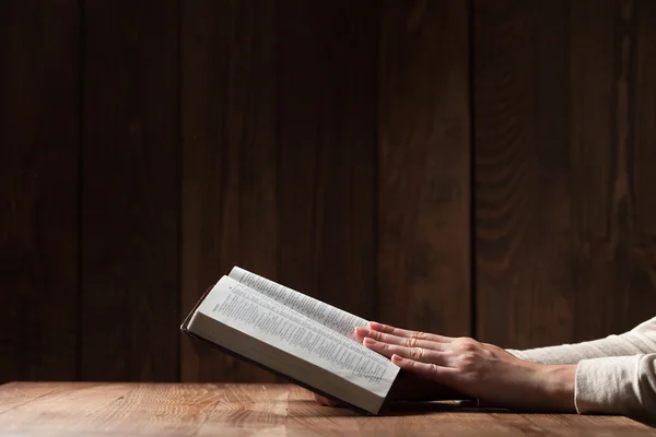 Γυναίκα διαβάζοντας τη Βίβλο μέσα στο σκοτάδι, πάνω από το ξύλινο τραπέζι — Φωτογραφία Αρχείου