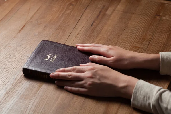 Donna mani sulla bibbia. sta leggendo e pregando sulla Bibbia — Foto Stock