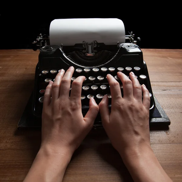 Manos escribiendo sobre una vieja máquina de escribir sobre un fondo de mesa de madera Fotos de stock