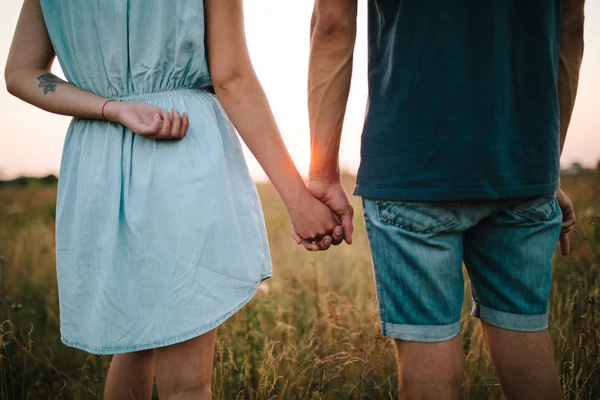 Casal segurando as mãos de pé no campo — Fotografia de Stock