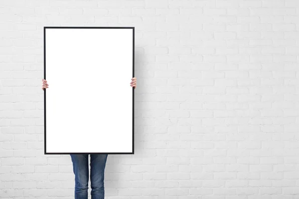 Woman with blank poster on wall background — Stock Photo, Image