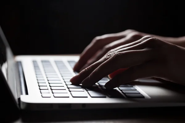 Mãos de mulher usando laptop na mesa de escritório, com copyspace no escuro — Fotografia de Stock