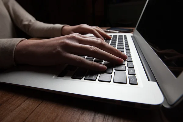 Manos de mujer usando el ordenador portátil en el escritorio de la oficina, con copyspace en la oscuridad —  Fotos de Stock
