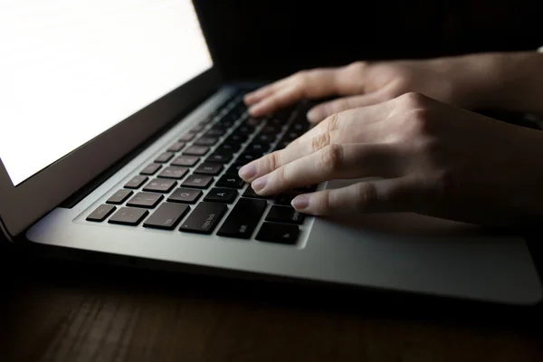 Manos de mujer usando el ordenador portátil en el escritorio de la oficina, con copyspace en la oscuridad —  Fotos de Stock