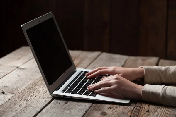 Manos de mujer usando el ordenador portátil en el escritorio de la oficina, con copyspace en la oscuridad — Foto de Stock