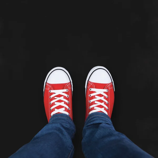 Füße tragen rote Schuhe auf schwarzem Hintergrund mit Platz für Text — Stockfoto