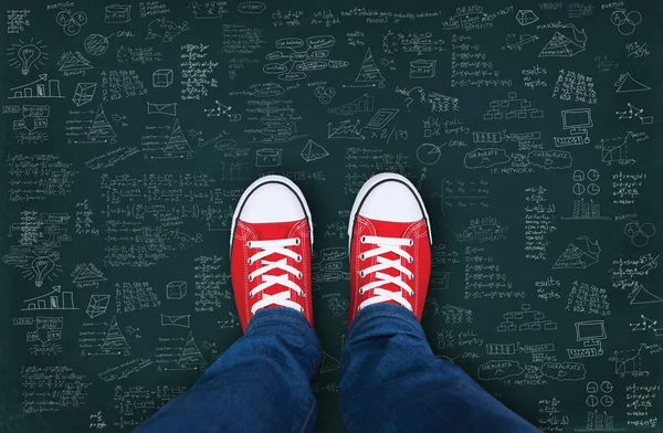 Feet wearing red shoes on black background with business plan — Stock Photo, Image