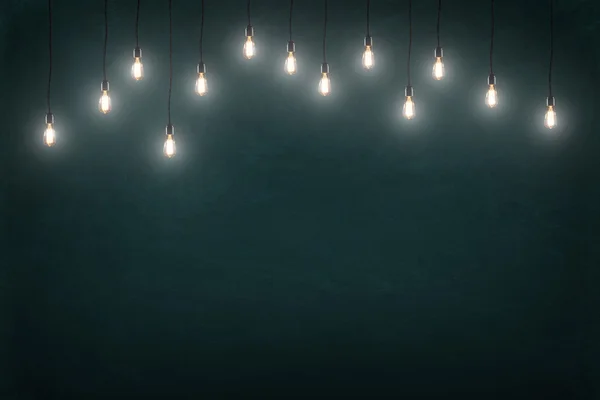 Light bulbs on dark chalkboard background — Stock Photo, Image