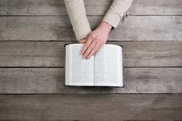 Donna mani sulla bibbia. sta leggendo e pregando sulla Bibbia — Foto Stock