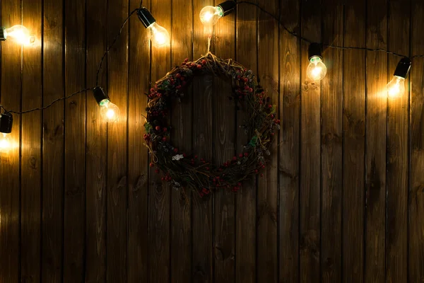 Glödlampor på mörk trä bakgrund med jul inredning — Stockfoto