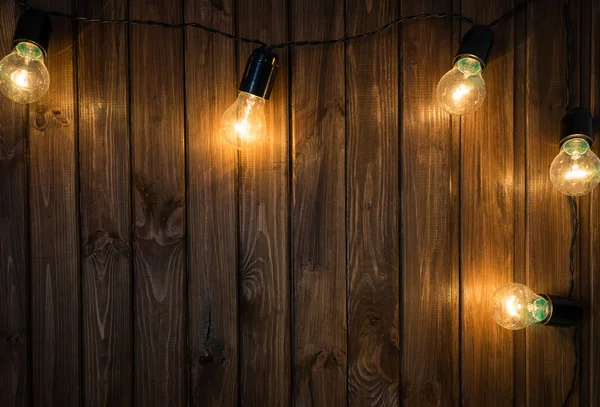 Bombillas de luz sobre fondo de madera oscura imagen real — Foto de Stock