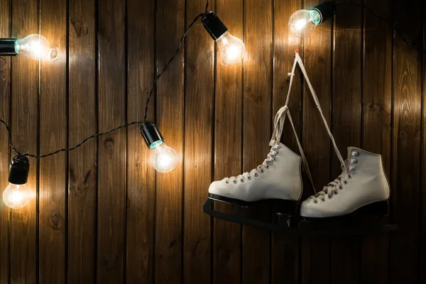 Pattini su ghiaccio contro una parete di legno con lampadine — Foto Stock