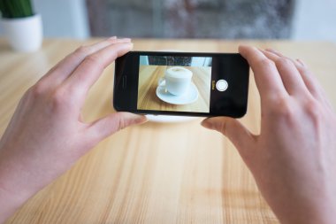 Bir fincan kahve ile akıllı telefonunu fotoğrafını kadın